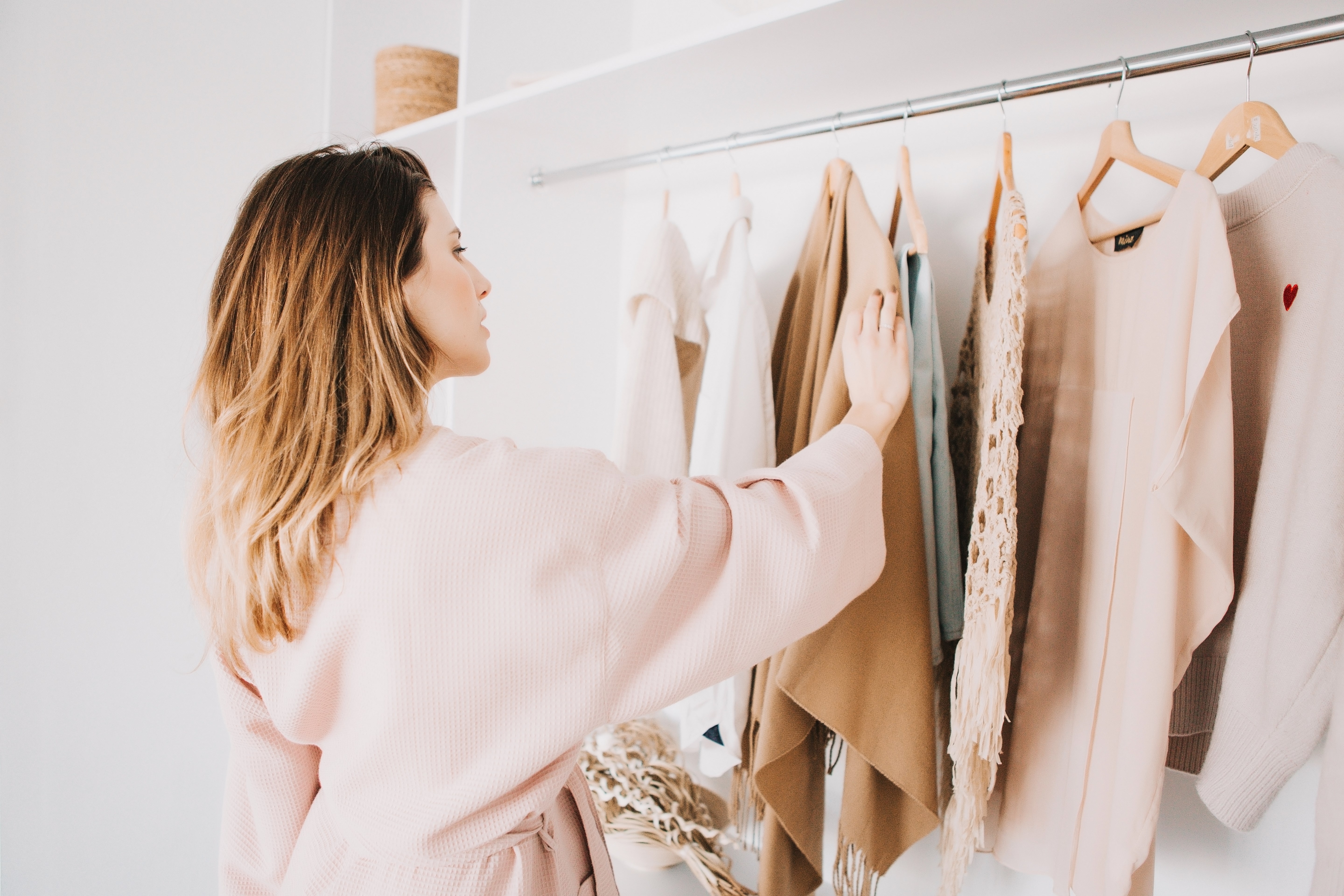 woman in bathrobe standing in front of hanger rack and trying to choose outfit dressing